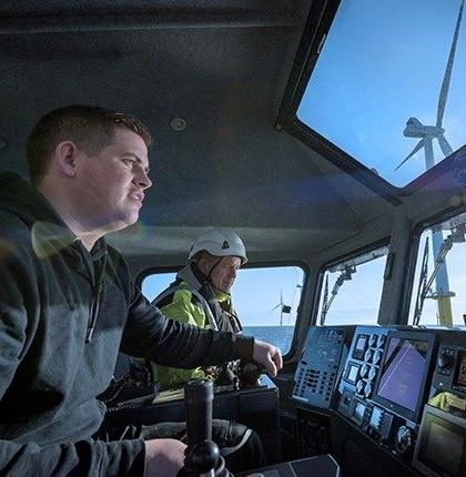 Two men navigating a commercial boat through the sea.